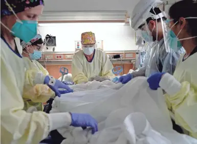  ?? PHOTOS BY HARRISON HILL/USA TODAY ?? Respirator­y therapist Julie Medeiros, center, and nurses prepare to “prone,” or flip, a patient to allow better expansion of the lungs at Providence Holy Cross Medical Center.