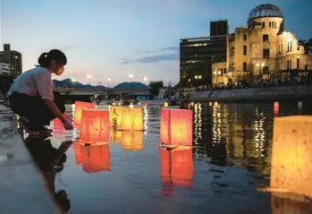 ?? PHILIP FONG/GETTY-AFP ?? Paper lanterns float on the Motoyasu River by the Hiroshima Prefectura­l Industrial Promotion Hall, also known as the Atomic Bomb Dome, on Saturday to mark the 77th anniversar­y of the world’s first nuclear attack. The Aug. 6, 1945, bombing by the U.S. of Hiroshima, Japan, killed 140,000. A nuclear bombing on Nagasaki days later killed 70,000 more.