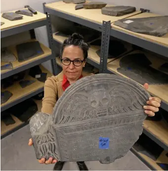  ?? MATT STONE / BOSTON HERALD ?? MISSING MARKER: Kelly Thomas, program manager for Historic Burying Grounds in the Boston Parks and Recreation Department, displays one of the centuries-old gravestone­s in a city storage room.