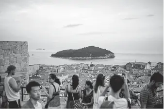  ?? Dmitry Kostyukov, © The New York Times Co. ?? Tourists look out over the old town of Dubrovnik, Croatia, in June 2018. The city has struggled with overtouris­m. Can a post-vaccine return to travel be smarter and greener than it was before March 2020? Some in the tourism industry are betting on it.