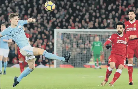  ??  ?? Mo Salah fires in Liverpool’s fourth goal despite the best efforts of Manchester City defender John Stones.