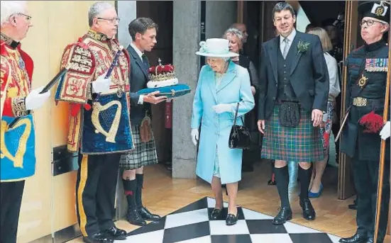  ?? ANDREW MILLIGAN / AFP ?? Isabel II inspeccion­a la corona en el Black and White Corridor después de la apertura de la sesión del Parlamento escocés ayer en Edimburgo