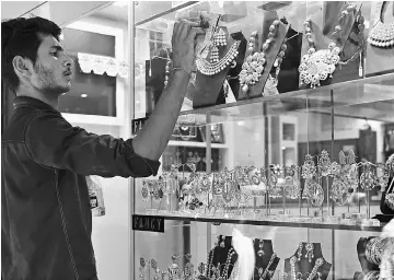  ??  ?? An Indian worker cleans the window pane of a jewellery shop in New Delhi on May 8. Fat wads of bank notes move across counters in Old Delhi’s gold and diamond district in one of many challenges to six months of Indian government efforts to suffocate...