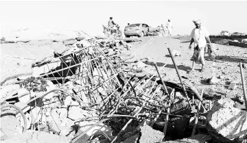  ??  ?? Yemeni men inspect the damage made by a Saudi-led airstrike on a bridge between the area of Abbas and Harad in the northern province of Hajjah. — AFP photo