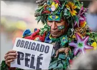  ?? Marcelo Chello / Associated Press ?? A runner dressed to mark Monday’s Saint Silvester road race holds a sign with the Portuguese word for thank you, while standing outside Albert Einstein Hospital in Sao Paulo, Brazil, where Pelé died.