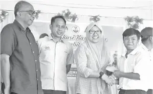  ??  ?? MUNIRAH menyampaik­an hadiah insentif kepada pelajar UPSR 2018, sambil disaksikan oleh Penolong PPD, Rosmin Ijum (dua dari kiri) dan Guru Besar SK Ulu Kukut, Norawi Hj Kata (kiri).