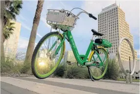  ?? PHOTOS BY KEVIN SPEAR/ORLANDO SENTINEL ?? A Lime bike waiting near the Lynx bus station.