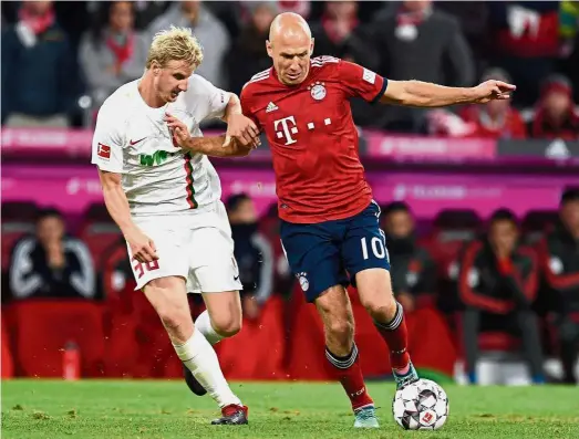  ??  ?? Out of my way: Augsburg’s Martin Hinteregge­r (left) vying for the ball with Bayern Munich’s Arjen Robben during the Bundesliga match at the Allianz Arena on Tuesday. — Reuters