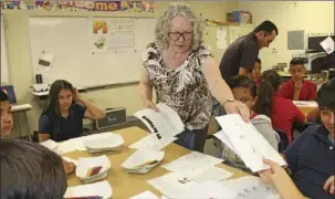  ??  ?? Peggy Ramirez (center), ECESD reading coach, hands out materials for game/art challenges on National Pi Day at De Anza Magnet School in El Centro on Tuesday. WILLIAM ROLLER PHOTO