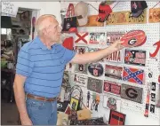  ?? Doug Walker / Rome News-Tribune ?? Charles Ledbetter puts up a UGA item among the collegiate collectibl­es in his Cave Spring General Store, 2 Rome Road.