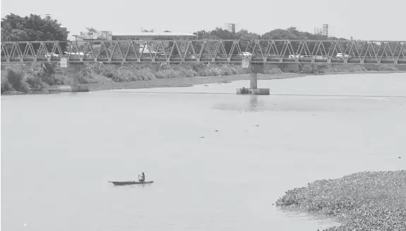  ?? (NEF LUCZON) ?? BOATING. A local resident paddles through Cagayan River on Wednesday, which part of the body of water is covered with water hyacinths. The city government through the local environmen­t office plans to remove them to avoid clogging of waterways.