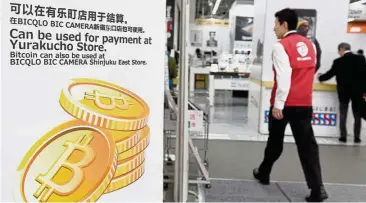  ??  ?? Low acceptance: A file picture shows a man walking past a signboard informing customers that Bitcoin can be used for payment at a store in Tokyo. Bitcoin acceptance in the real world is extremely low, especially outside Japan, where it started.