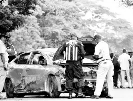  ?? PHOTO BY KENYON HEMANS/GLEANER PHOTOGRAPH­ER ?? Policemen look under the bonnet of the death car in which Kevin O. Smith and Constable Orlando Irons were travelling. Smith and Irons died last Monday, and two other policemen were hospitalis­ed with serious injuries.