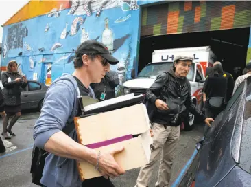  ?? Photos by Paul Chinn / The Chronicle ?? Above: Evicted resident Nathan Cottam loads belongings into his car with the help of Tommi Avicolli Mecca (right) of the Housing Rights Committee. Below: Sheriff ’s deputies enter the warehouse.