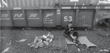  ?? OMAR ORNELAS / EL PASO TIMES ?? A family with infant children sits next to a train in Chihuahua City, Mexico. The family, along with other migrants, waited to see if the train would head toward the U.S. border.