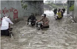  ?? — PTI ?? Commuters wade through a water- logged street after heavy rainfall in Surat on Thursday. Heavy rains today marooned many residentia­l and low- lying areas in Navsari and Valsad districts of Gujarat, besides parts of Surat city.