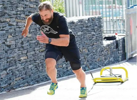  ?? Foto: Siegfried Kerpf ?? AEV Verteidige­r Arvids Rekis zieht den knapp 60 Kilogramm schweren Widerstand Schlitten eine Asphaltram­pe am Eisstadion hoch. In einer Trainingsg­ruppe bereiten sich die Panther auf die neue Saison vor.