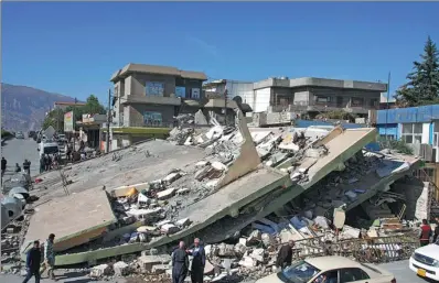  ?? SHWAN MOHAMMED / AGENCE FRANCE-PRESSE ?? People gather around a leveled building in the mountainou­s town of Darbandikh­an in Iraqi Kurdistan on Monday, following a magnitude 7.3 quake that hit the Iraq-Iran border area.