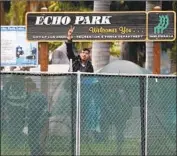  ?? Damian Dovarganes Associated press ?? AN ACTIVIST f lashes the peace sign as city sanitation employees begin work at Echo Park Lake.