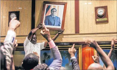  ?? Picture: AFP/JEKESAI NJIKIZANA ?? LEADERSHIP CHANGE: People remove the portrait of former Zimbabwean president Robert Mugabe from the wall at the Internatio­nal Conference Centre in Harare after his resignatio­n. The Zimbabwean parliament was sitting in the centre