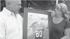  ?? 2014 PHOTO BY MELISSA NELSON- GABRIEL, AP ?? Brian and Kathy Haugen hold a photo of their son Taylor, who died playing high school football in 2008.