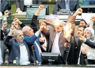  ??  ?? Iranian MPs burn US flag and make provocativ­e gestures in parliament yesterday
