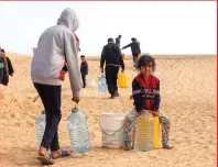  ?? ?? Palestinia­ns transport water to a camp for displaced people in Rafah.