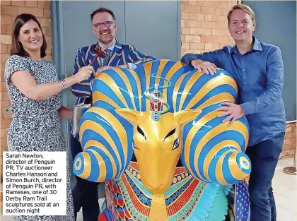  ??  ?? Sarah Newton, director of Penguin PR, TV auctioneer Charles Hanson and Simon Burch, director of Penguin PR, with Rameses, one of 30 Derby Ram Trail sculptures sold at an auction night