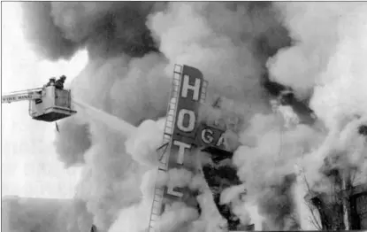  ?? Penticton Herald file photo ?? Firefighte­rs in the bucket of the Penticton Fire Department’s snorkel truck train their hoses on the front of the Three Gables Hotel, as smoke billows from the inferno that levelled the aging building.