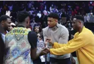  ?? The Associated Press ?? ■ Millwaukee Bucks’ Giannis Antetokoun­mpo, center, along with brothers Thanasis Antetokoun­mpo, right, and Alex Antetokoun­mpo award NFL player DK Metcalf the MVP award at the NBA All-star Celebrity Game Friday in Salt Lake City.