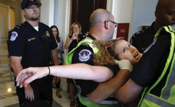  ?? JACQUELYN MARTIN/THE ASSOCIATED PRESS ?? Stephanie Woodward, of Rochester, N.Y., who has spina bifida and uses a wheelchair, is removed from a sit-in at Senate Majority Leader Mitch McConnell’s office as she and other disability rights advocates protest proposed funding caps to Medicaid in...