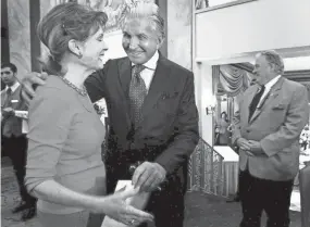  ?? THE MEMPHIS COMMERCIAL APPEAL, FILES ?? March 21, 2012: Actor George Hamilton, right, hugs former Miss America Lynda Shea during a meet-and-greet event with The Tiara Tea Society at Chez Philippe in The Peabody hotel. Shea was showing Hamilton a picture of when he crowned her Miss University at Ole Miss in 1959.