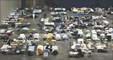  ??  ?? RELIEF CENTER: Refugees from the Gulf Coast region hit by Hurricane Katrina rest on cots in the Hot Springs Convention Center’s arena on Sept. 6, 2005. The Garland County Chapter of the American Red Cross had set up an emergency relief center at the...