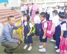  ??  ?? Ashlyn Leann A, a Year One pupil of SK St FrancisXav­ier,Keningau being calmed down by teacher Fredolin Majip on the first day of schooling.