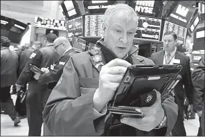  ?? AP/ RICHARD DREW ?? Trader Richard Newman works on the fl oor of the New York Stock Exchange on Wednesday. Stocks closed down slightly on Wall Street as the market stabilized after three days of tumult.