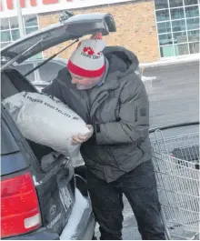  ?? JOE GIBBONS/THE TELEGRAM ?? George Cooper of Conception Bay South puts a bag of wood pellets into his vehicle Wednesday at Canadian Tire on Hebron Way in St. John’s.