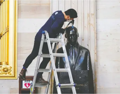 ?? JOSHUA ROBERTS / REUTERS ?? Gompo Yarmolinsk­y cleans the bust of Martin Luther King, Jr. after a mob stormed the U.S. Capitol last week. GOP leaders in the House on Tuesday refrained from urging their members to vote against impeaching Donald Trump.