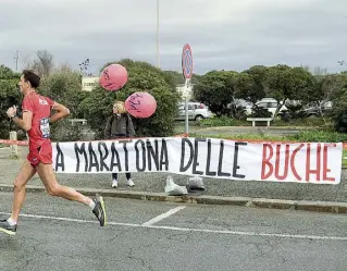  ??  ?? Protesta Lo striscione sulle buche esposto ieri durante la maratona Roma-Ostia