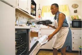  ?? Sarahbeth Maney / Special to The Chronicle ?? Renee McGhee puts a pan of bread pudding into her oven. McGhee was hit by a series of economic setbacks and says she’s grateful for the help she received.