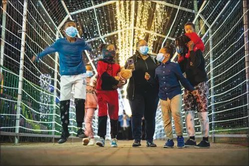  ?? (AP/Jerome Delay) ?? Children walk Dec. 12 through a light tunnel at the Johannesbu­rg, South Africa, city zoo.