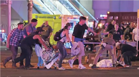  ?? ETHAN MILLER, GETTY IMAGES ?? An injured person is cared for at the intersecti­on of Tropicana Avenue and Las Vegas Boulevard after the mass shooting, the worst in U.S. history. The shooter was found dead in his hotel room after he killed dozens.