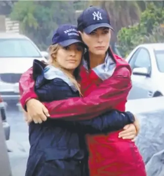  ??  ?? House Rules contestant­s Ella Cuthbert and Kate Whiting huddle as Cyclone Debbie hits.