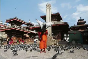  ?? — NIRANJAN SHRESTA/AP ?? A Nepalese monk waiting for alms in Basantapur Durbar Square, Kathmandu. The square is located in front of the royal palace, a UNESCO World Heritage site.