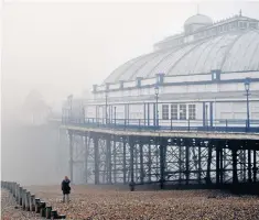  ??  ?? Taking the air: a woman on the beach at Eastbourne appears indistinct beside the pier