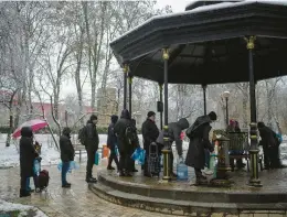  ?? EVGENIY MALOLETKA/AP ?? Ukrainians wait in line to collect water Thursday in Kyiv. “Strikes against civilian infrastruc­tures are war crimes,” French President Emmanuel Macron tweeted.