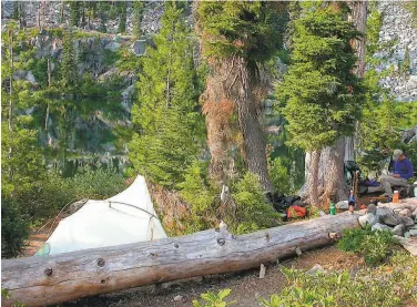  ?? Tom Stienstra / The Chronicle ?? Michael Furniss writes in his trail diary at a camp at Monument Lake in the Marble Mountain Wilderness.