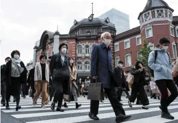  ?? ?? Labour conditions: Commuters walk outside Tokyo station. The number of people with jobs increased by around half a million compared to the year before, led by gains in the hospitalit­y and medical sectors. — AFP