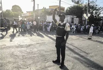  ?? ODELYN JOSEPH AP ?? A police officer controls security on a street in Port-au-Prince, Haiti, on Saturday. A gang stormed a key part of the city and battled with police throughout the day, leaving at least three officers dead and another missing.