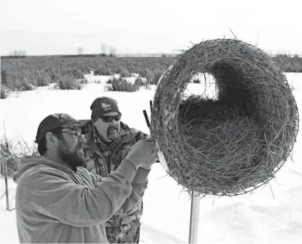  ?? PAUL A. SMITH ?? Matt Bennett (left) of Concord and Paul Wait of New London fasten a hen house to its support at Prince's Point Wildlife Area near Whitewater. The structure is designed to provide a safe nesting site for waterfowl.