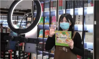  ??  ?? An employee of the Zhongshuge Bookstore in Beijing recommends a book through live-streaming on March 18